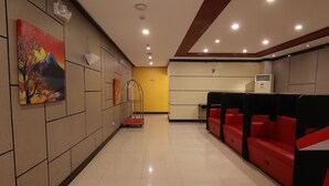 A hotel lobby with a reception desk, red seating area, and a painting on the wall. - Hotel Sogo Makati Ave. (Makati)