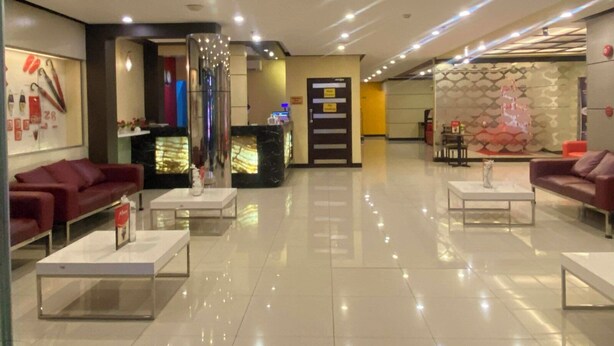 A modern hotel lobby with a reception desk, seating area, and a decorative wall. - Hotel Sogo Makati Ave. (Makati)