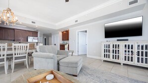 Un salón amplio con una lámpara moderna, un televisor de pantalla plana y una mesa de centro de madera con estrellas de mar.