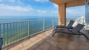 A balcony with two wicker lounge chairs, a tiled floor, and a view of the ocean. - A Getaway at the Beach is What you Need~ Book Now (Gulf Shores)