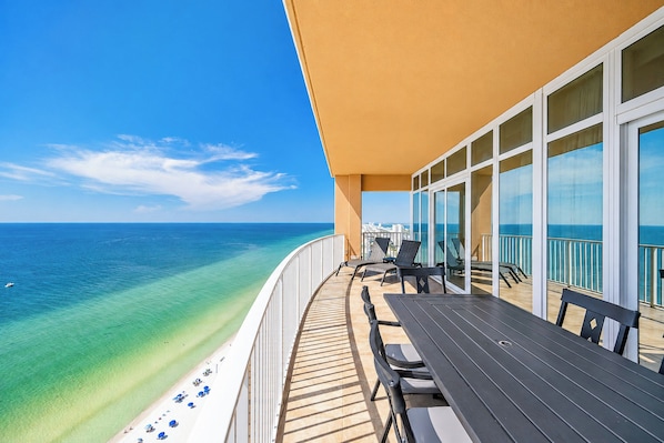 A balcony with a view of the ocean, outdoor seating, and a clear sky. - A Getaway at the Beach is What you Need~ Book Now (Gulf Shores)