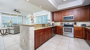 Cocina amplia con encimeras de granito, gabinetes de madera y electrodomésticos de acero inoxidable.