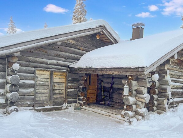 A log cabin with a snow-covered roof and a wooden door. - Kelotorppa a by Interhome (Kuusamo)