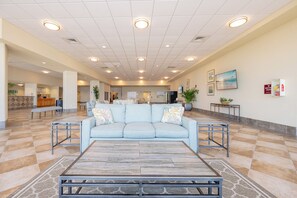 Eine geräumige Lobby mit einem hellblauen Sofa, einem Couchtisch und einem gefliesten Boden.