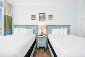 A hotel room with two beds, a nightstand with a lamp, and three framed pictures on the wall.