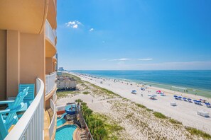 Un balcon d’hôtel avec vue sur une plage, une piscine et un poste de surveillance des sauveteurs.