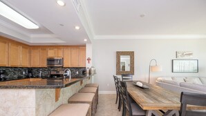 Una cocina moderna con una isla central, armarios de madera y una zona de comedor con mesa y sillas de madera.