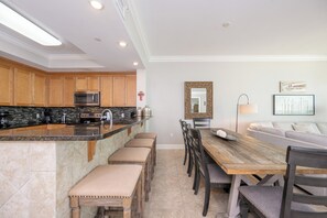 A modern kitchen with a central island, wooden cabinets, and a dining area with a wooden table and chairs.
