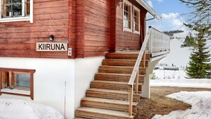 A wooden house with a sign reading "KIRUNA" and a staircase leading to a deck.