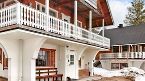 A two-story wooden house with white railings and a balcony.