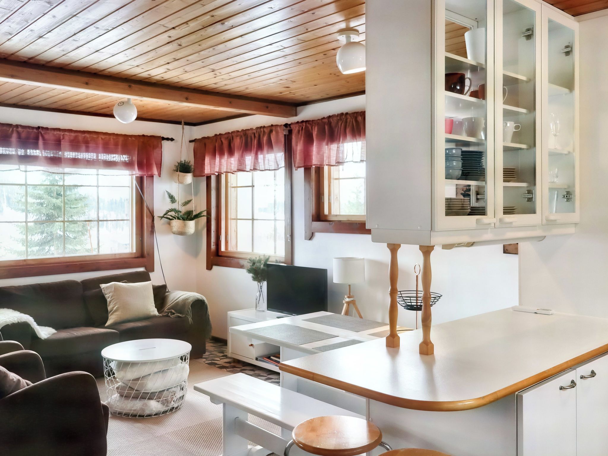 Um espaço de estar moderno com sofá, mesa de centro, TV e cozinha equipada com armários e bancada.