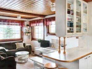 A modern living space with a sofa, a coffee table, a TV, and a kitchen area with cabinets and a countertop.