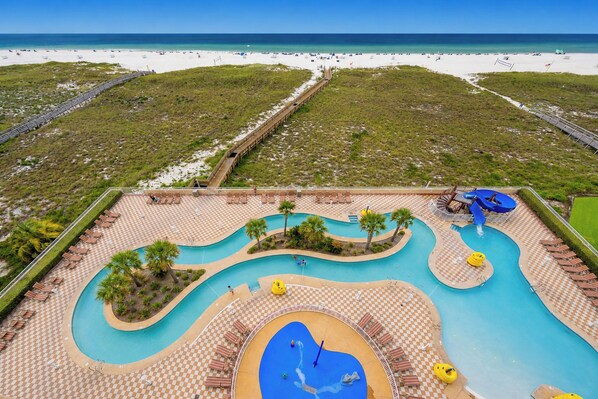 A resort with a large pool area, a beach, and a boardwalk.