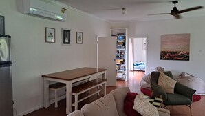 Un saló amb una taula de fusta, un sofà, un armari verd i un quadre a la paret.