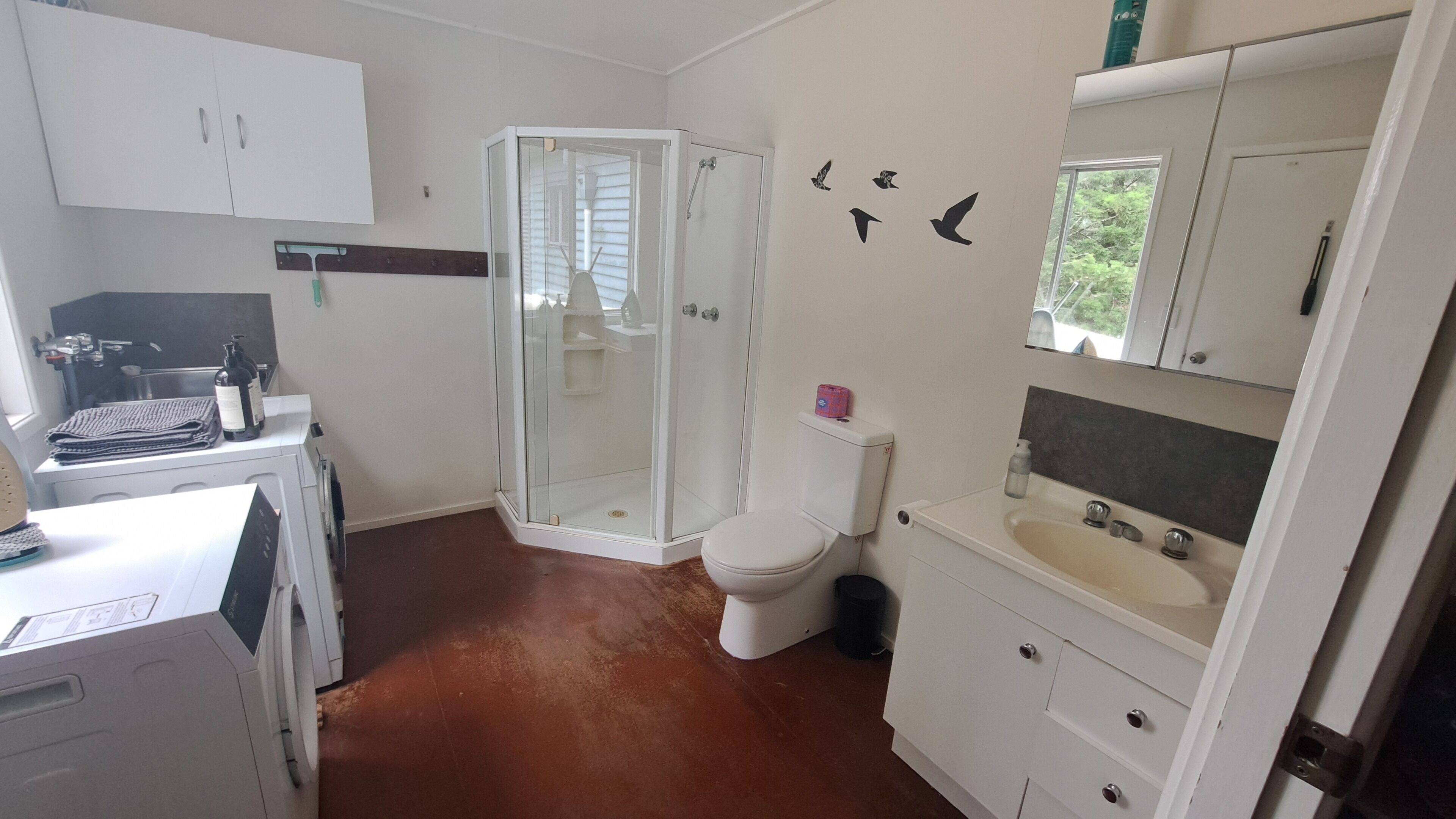 A bathroom with a shower, toilet, sink, and cabinets.