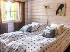 A bed with a star-patterned bedspread, a heart-shaped wall clock, and a framed picture on the wall.