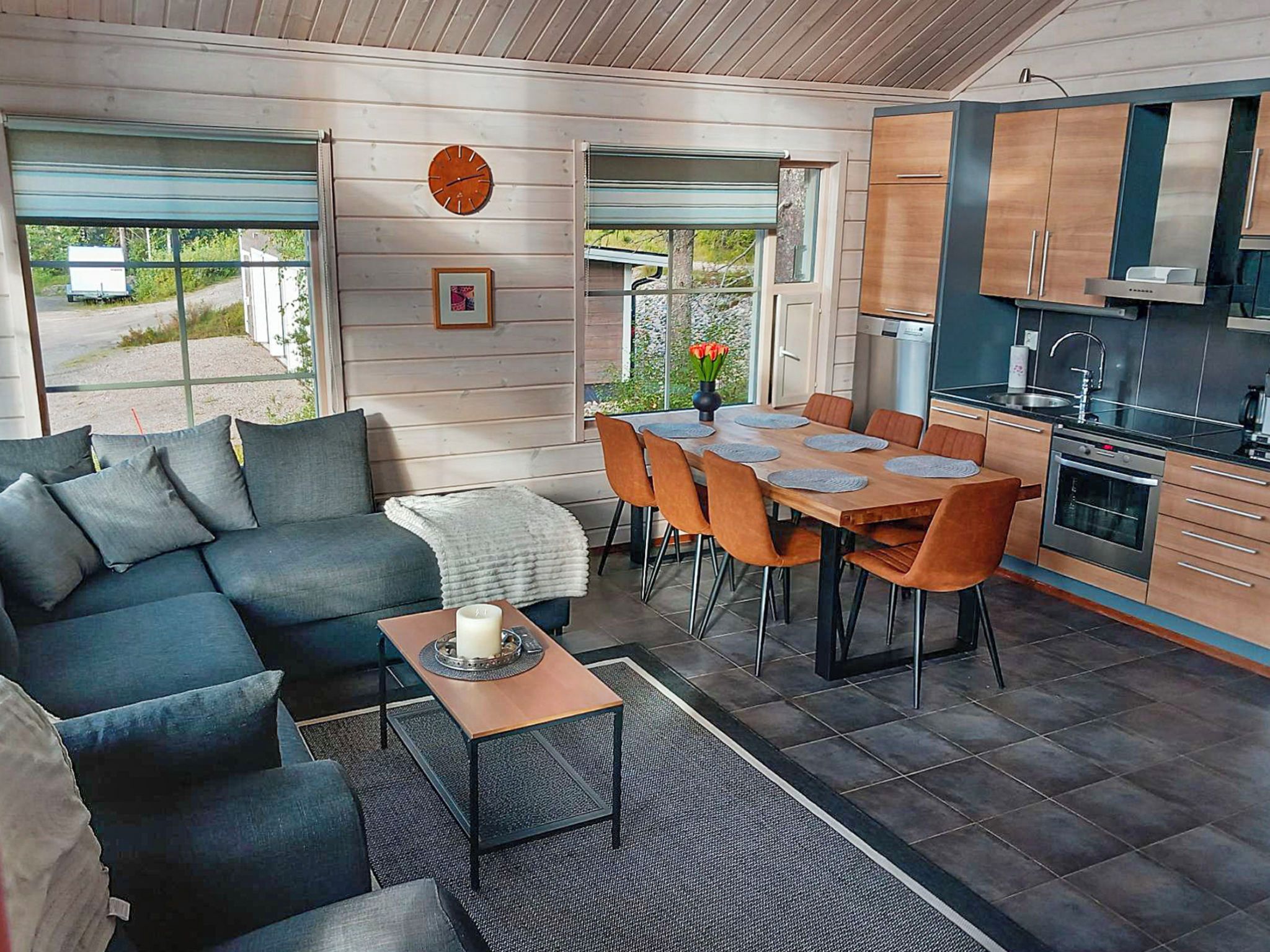 Et moderne opholdsrum med sofa, spisebord, stole og et køkken.