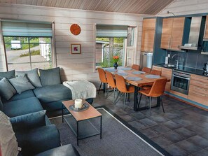 A modern living space with a sofa, dining table, chairs, and a kitchen area.