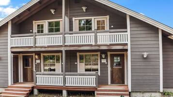A two-story building with a balcony, a front door, and a set of steps leading to the entrance.