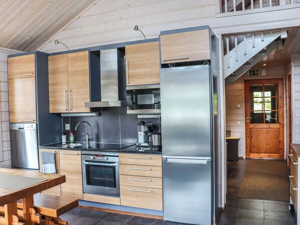 A modern kitchen with stainless steel appliances, wooden cabinets, and a built-in oven.