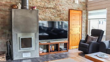 Una sala de estar con pared de piedra, chimenea, televisor, sofá y puerta de madera.