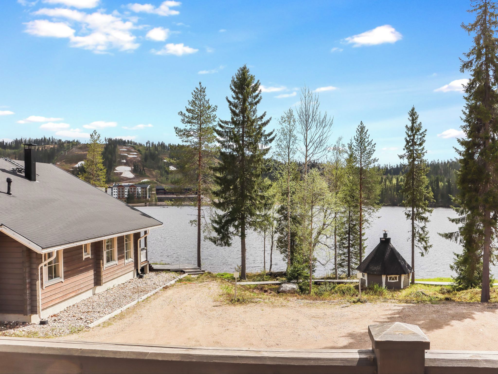 A lakeside view with a wooden building, a small cabin, and a dock extending into the water.