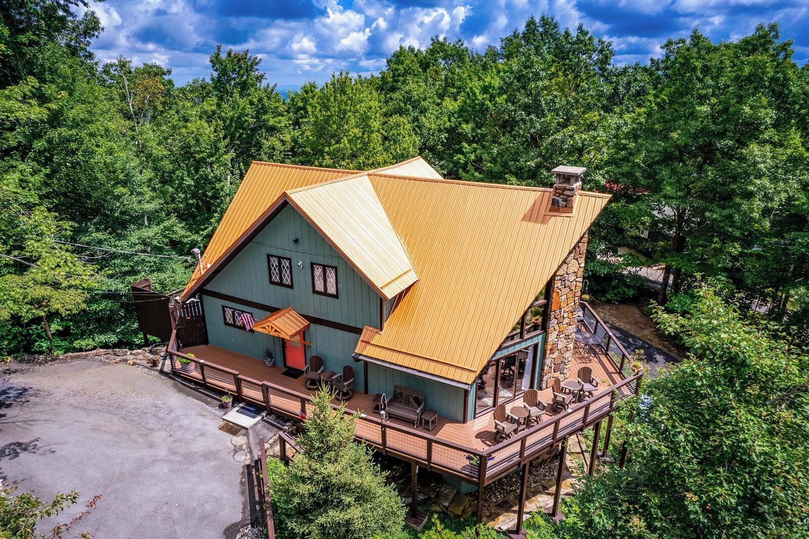 A two-story house with a wooden deck and a stone chimney.
