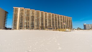 A large, multi-story hotel with numerous balconies, situated on a sandy beach. - Gorgeous Gulf Front view @ Phoenix V, Outdoor Pool, Hot tub & Splash Pad!! (Orange Beach)