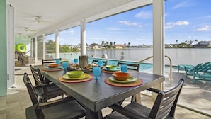 Comedor con vistas a un lago, mobiliario exterior y piscina.