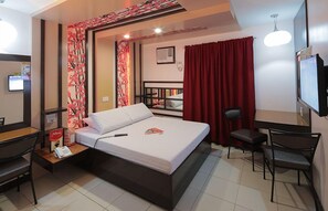 A hotel room with a bed, a desk with a telephone, a chair, a TV, and a red curtain. - Hotel Sogo Timog Ave. (Quezon City)