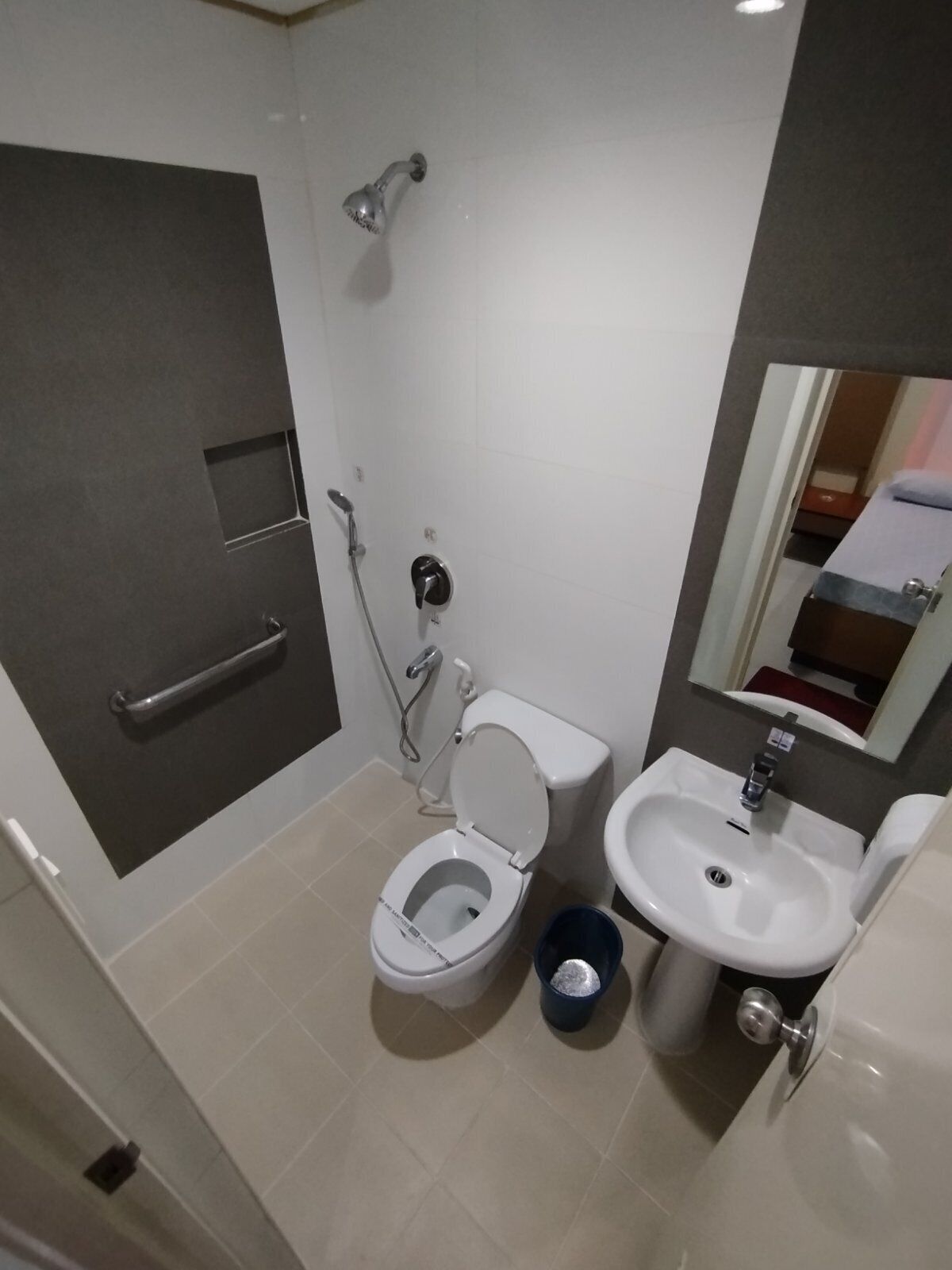 Une salle de bain équipée de toilettes, d’un lavabo, d’une douche et d’une barre d’appui.