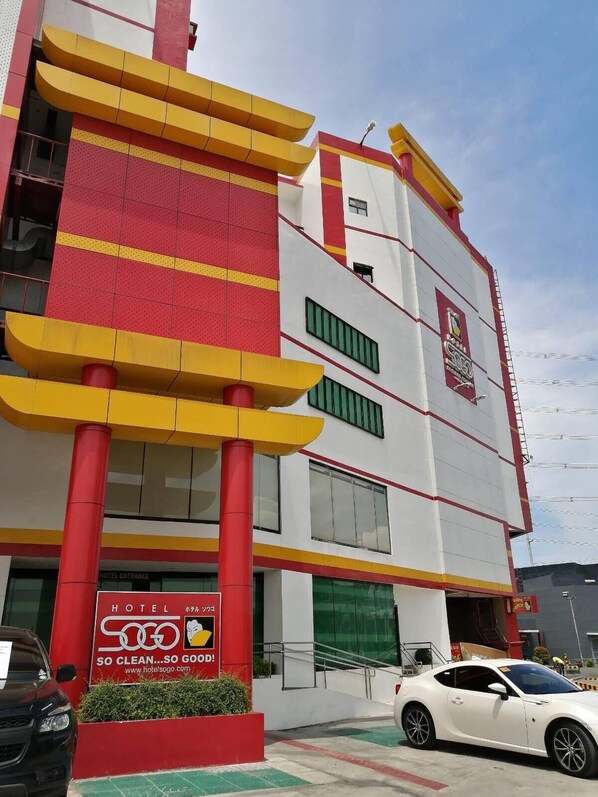 A hotel with a modern design, featuring a prominent red and yellow facade, a visible entrance, and a sign indicating it is a hotel. - Hotel Sogo Molino (Bacoor City)