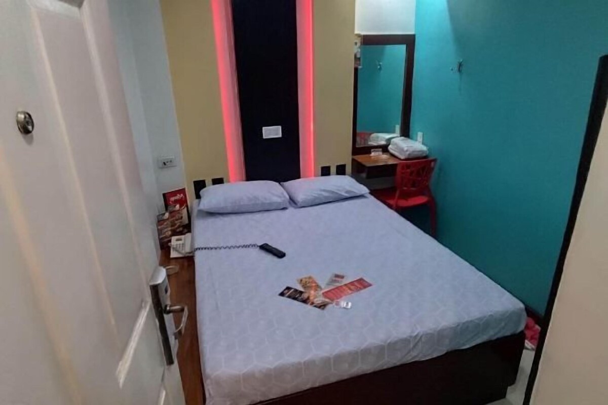 Quarto pequeno e compacto com uma cama de solteiro, uma escrivaninha e uma cadeira.