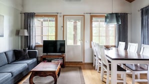 A living room with a sofa, coffee table, TV, and dining area with chairs and a table. - Tahkon klubitie 2 b by Interhome (Nilsiä)