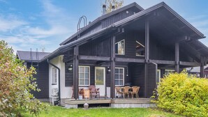 A two-story wooden house with a porch, outdoor seating, and a well-maintained lawn. - Tahkon klubitie 2 b by Interhome (Nilsiä)