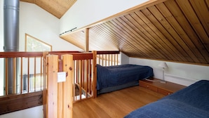A loft bedroom with a sloped ceiling, wooden beams, a metal chimney, and a view of the outdoors. - Tahkon klubitie 2 b by Interhome (Nilsiä)