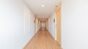 Ein langer, schmaler Korridor mit Holzboden und weißen Wänden.