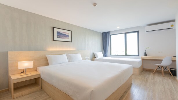 Ein Hotelzimmer mit einem großen Bett, Nachttischen, einem Schreibtisch, einem Sessel, einem Fenster und einem Bild an der Wand.