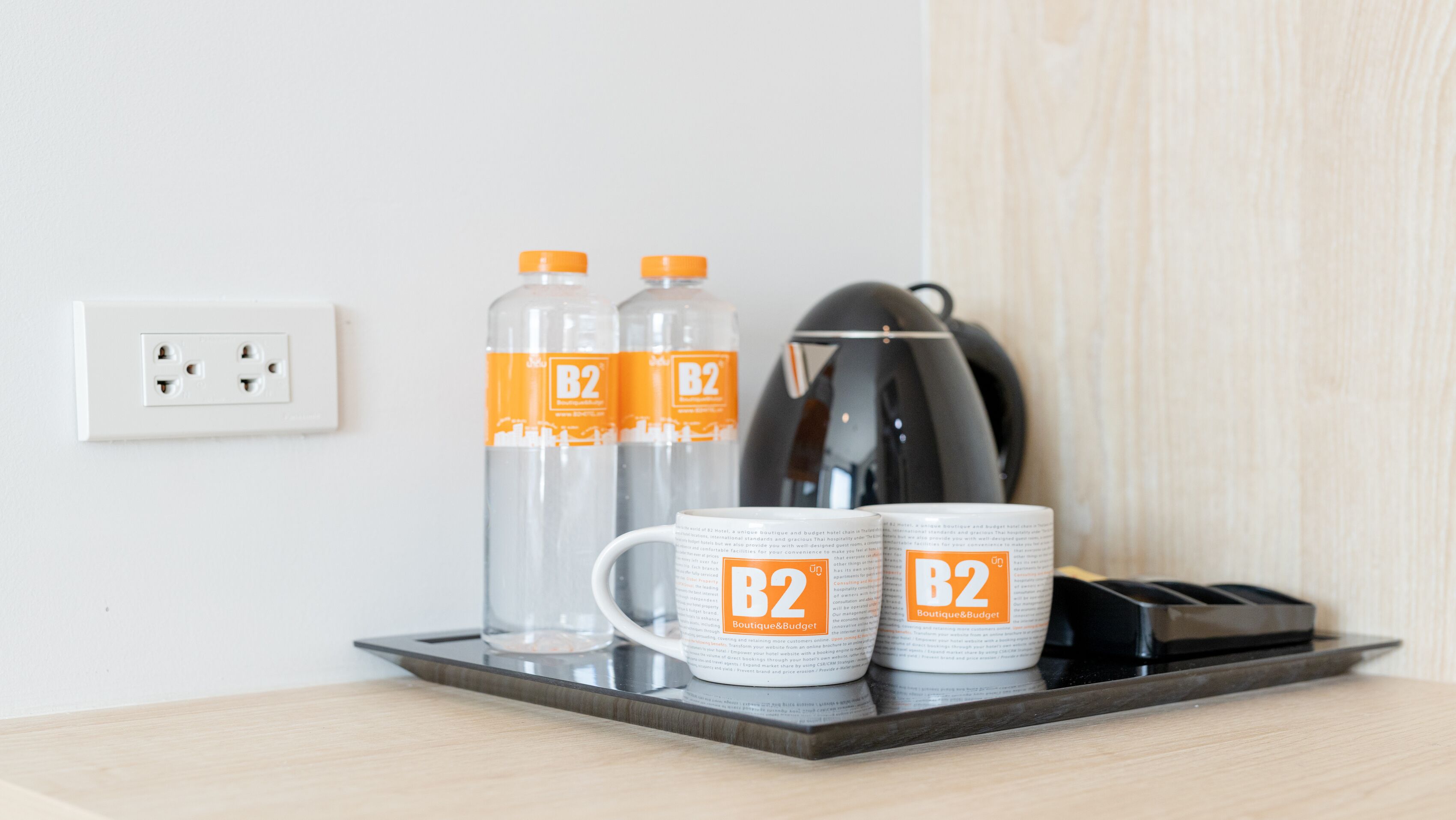 A tray with two B2 branded water bottles and two B2 branded mugs on a table.