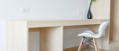 A modern, minimalist workspace with a wooden desk and a white chair.