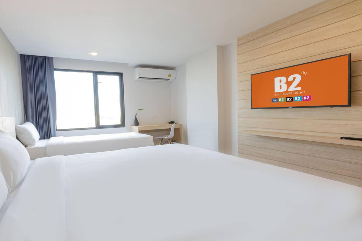 A hotel room with a large bed, a desk, and a TV displaying 'B2 Boutique&Budget'.