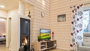 Ein gemütliches Wohnzimmer mit Kamin, Fernseher und einer Couch.