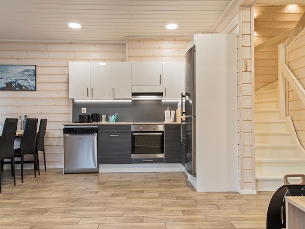 Een koelkast, een magnetron, een vaatwasser, kookgerei, borden en bestek