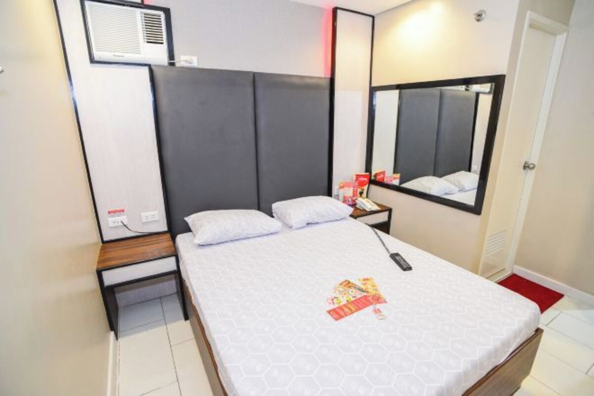 Une chambre d’hôtel comprenant un lit, une table de chevet, une commode et un miroir.