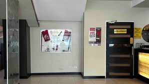 Eine Hotellobby mit einer Rezeption, einem an der Wand befestigten Plakat und einer Tür mit der Aufschrift 'HOTEL ENTRANCE'.