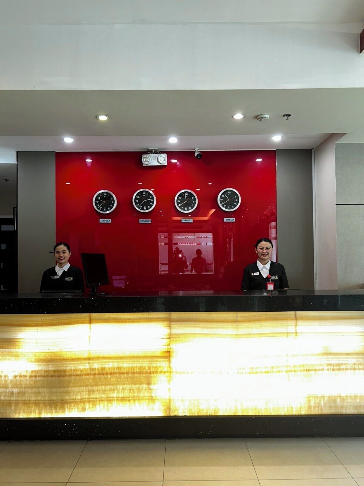 A reception desk with clocks indicating time in Manila, London, Sydney, and Tokyo.