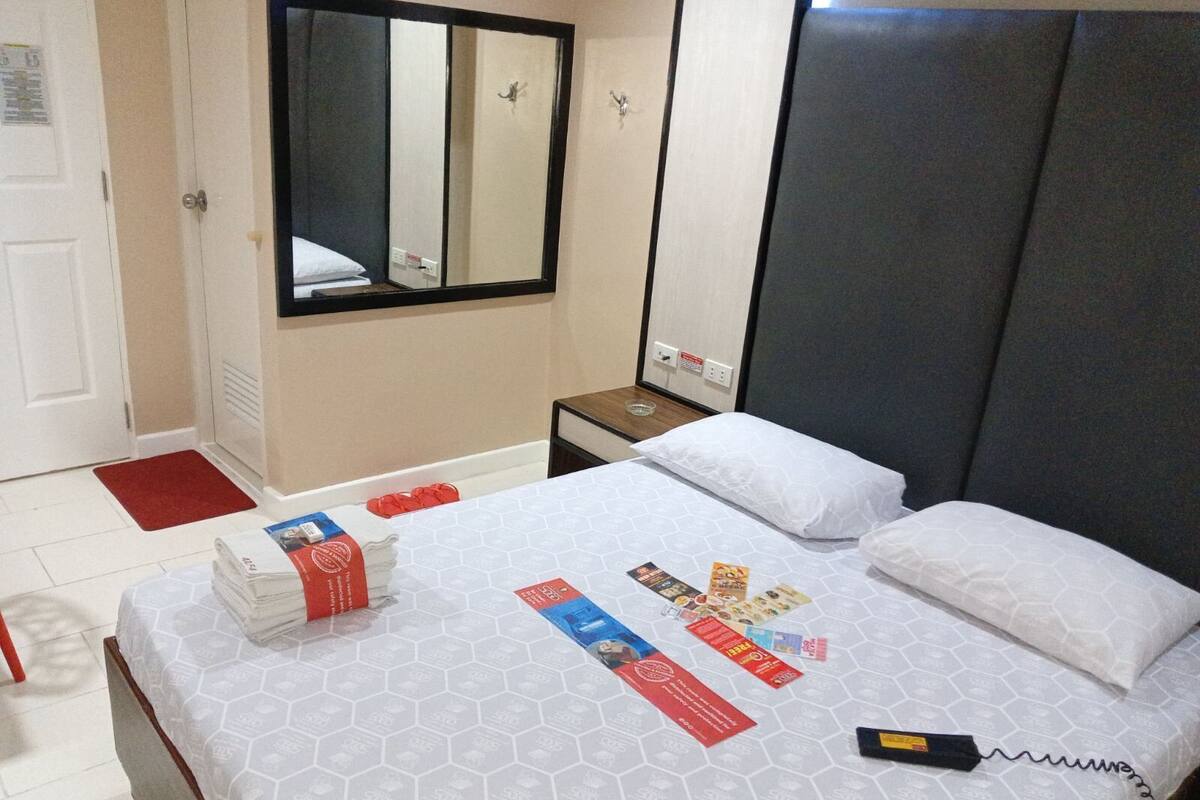 Ein Hotelzimmer mit Bett, Nachttisch, Spiegel und einer roten Matte auf dem Boden.