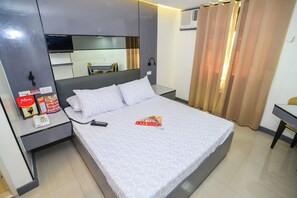 A hotel room with a bed, bedside table, a mirror, a desk, and a chair.