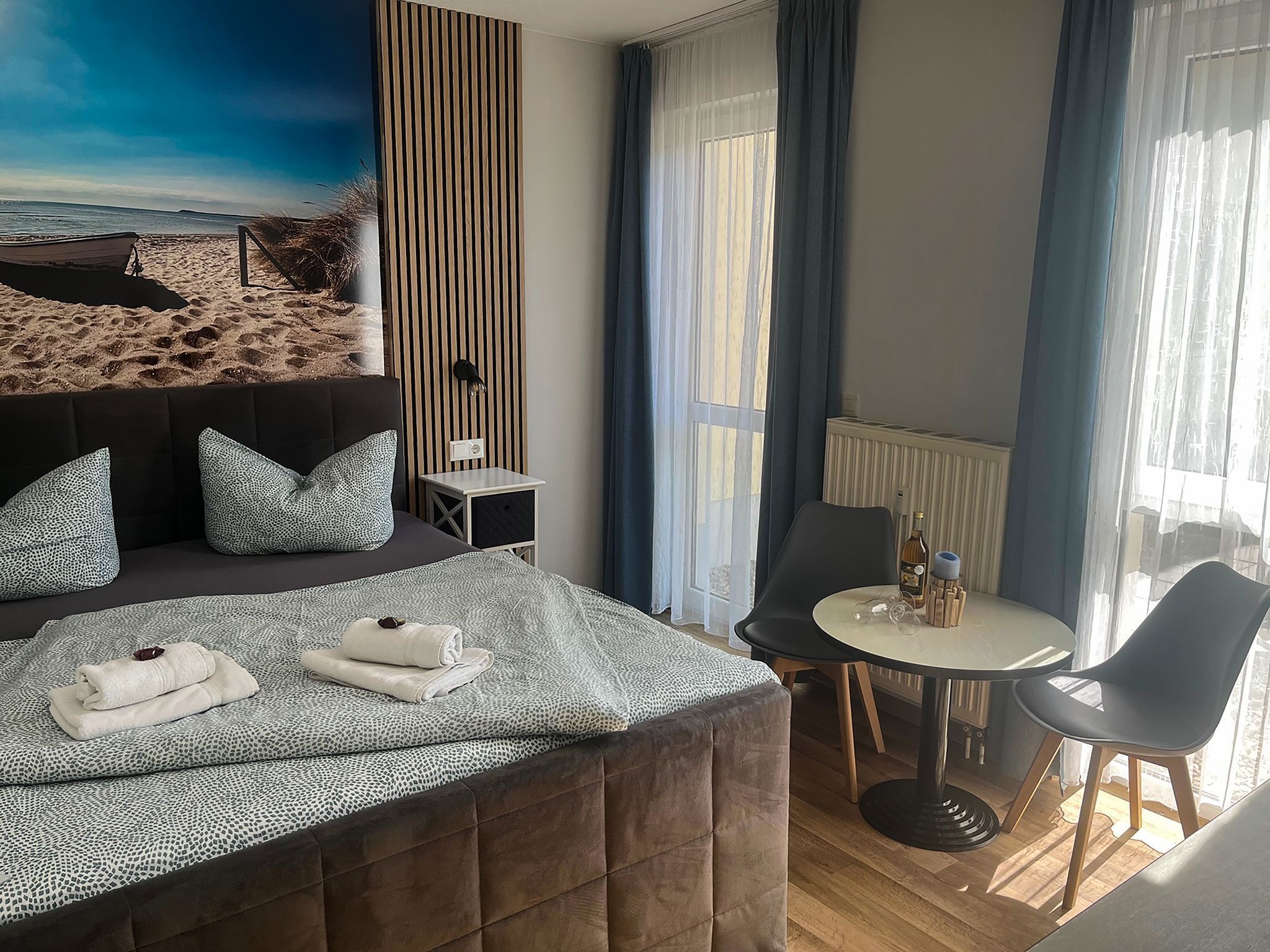 Habitación de hotel con cama, una mesita, una silla y vista a la playa.