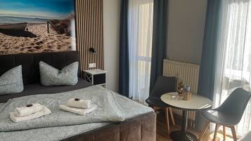 Habitación de hotel con cama, una mesita, una silla y vista a la playa.
